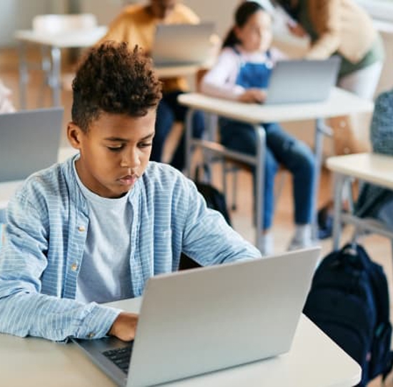 Child working on a laptop PC in a classroom.