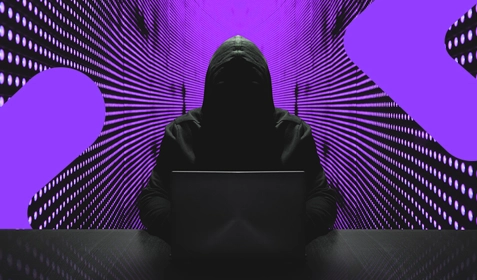 Person with hood up working on a laptop.