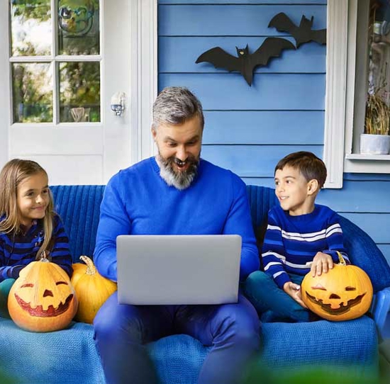 Father and 2 children viewing laptop PC