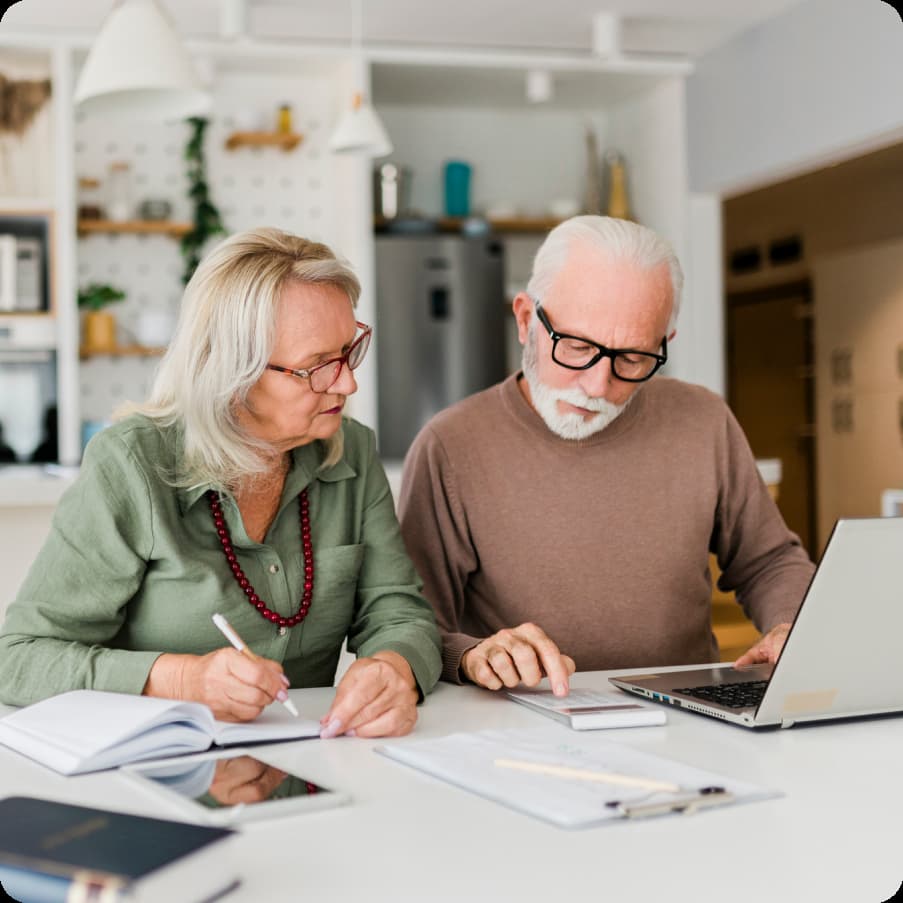 Older couple working on tax documents on a laptop PC.