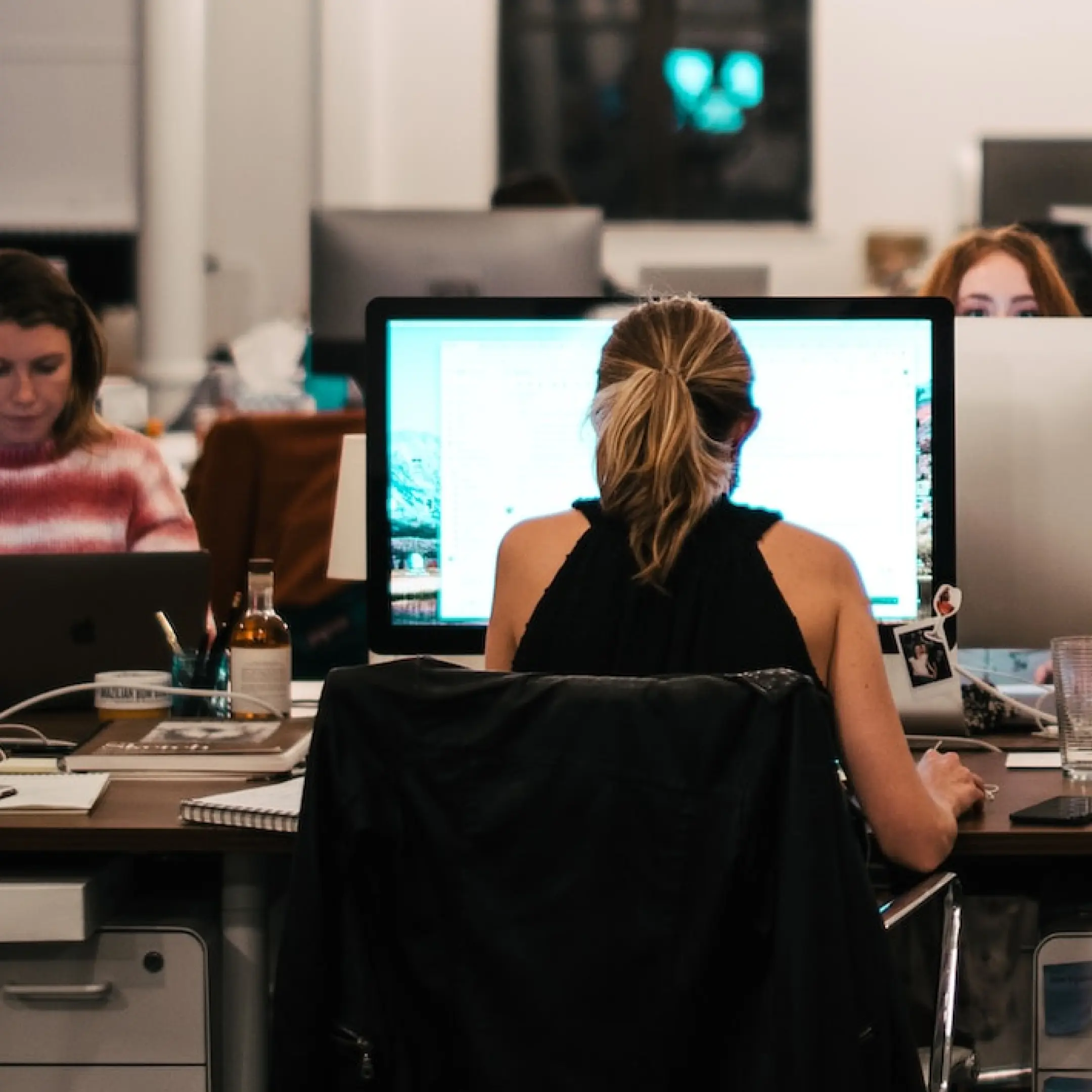 Photo of woman's back as she sits working on PC.