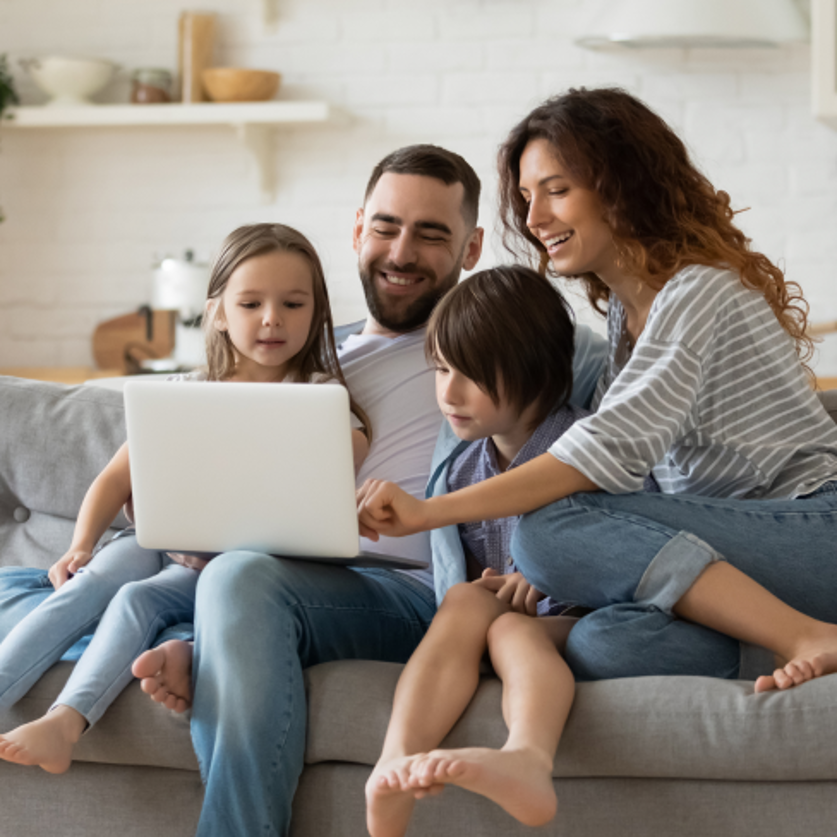 Family of 4, sitting on couch focused on the laptop