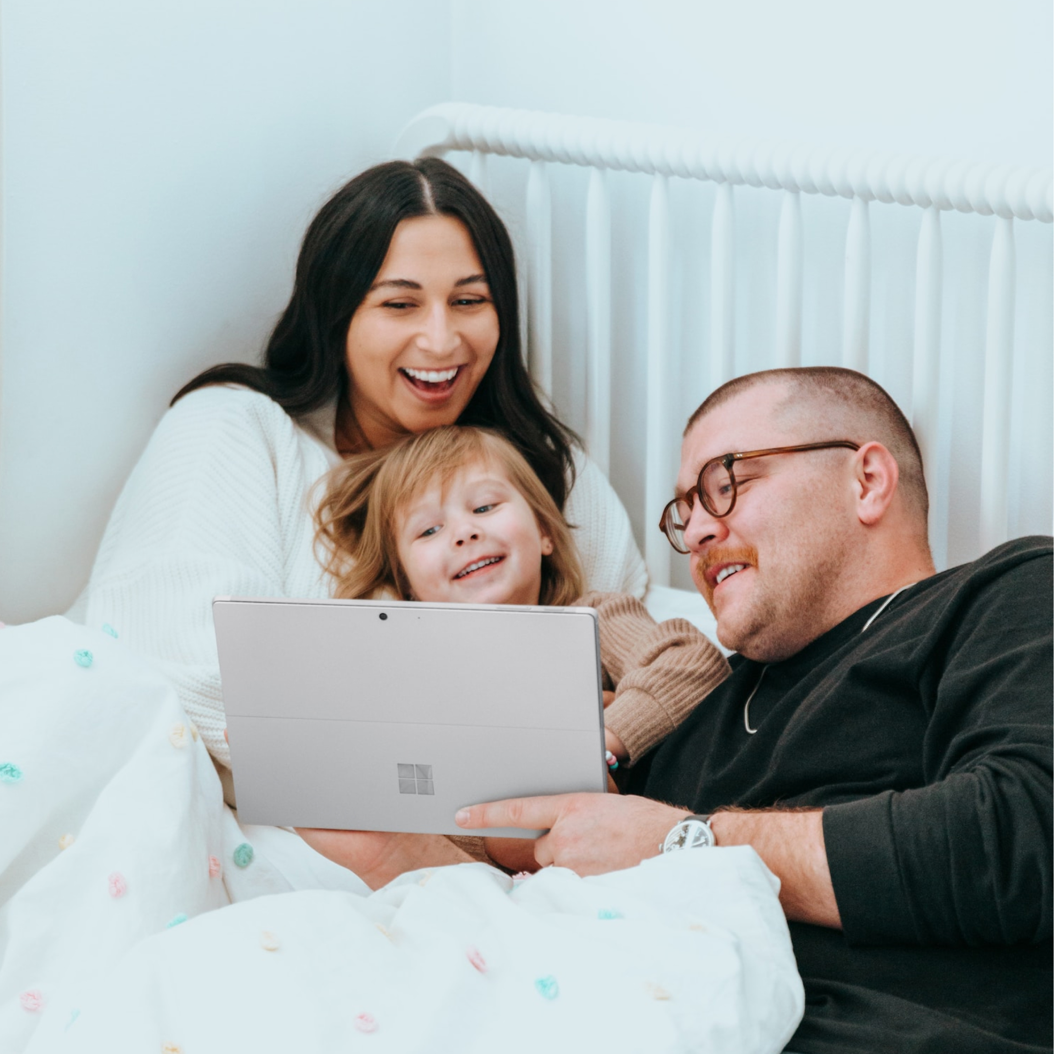 Smiling woman, toddler, and man look at the laptop he’s holding to see how their photos are protected from data loss.