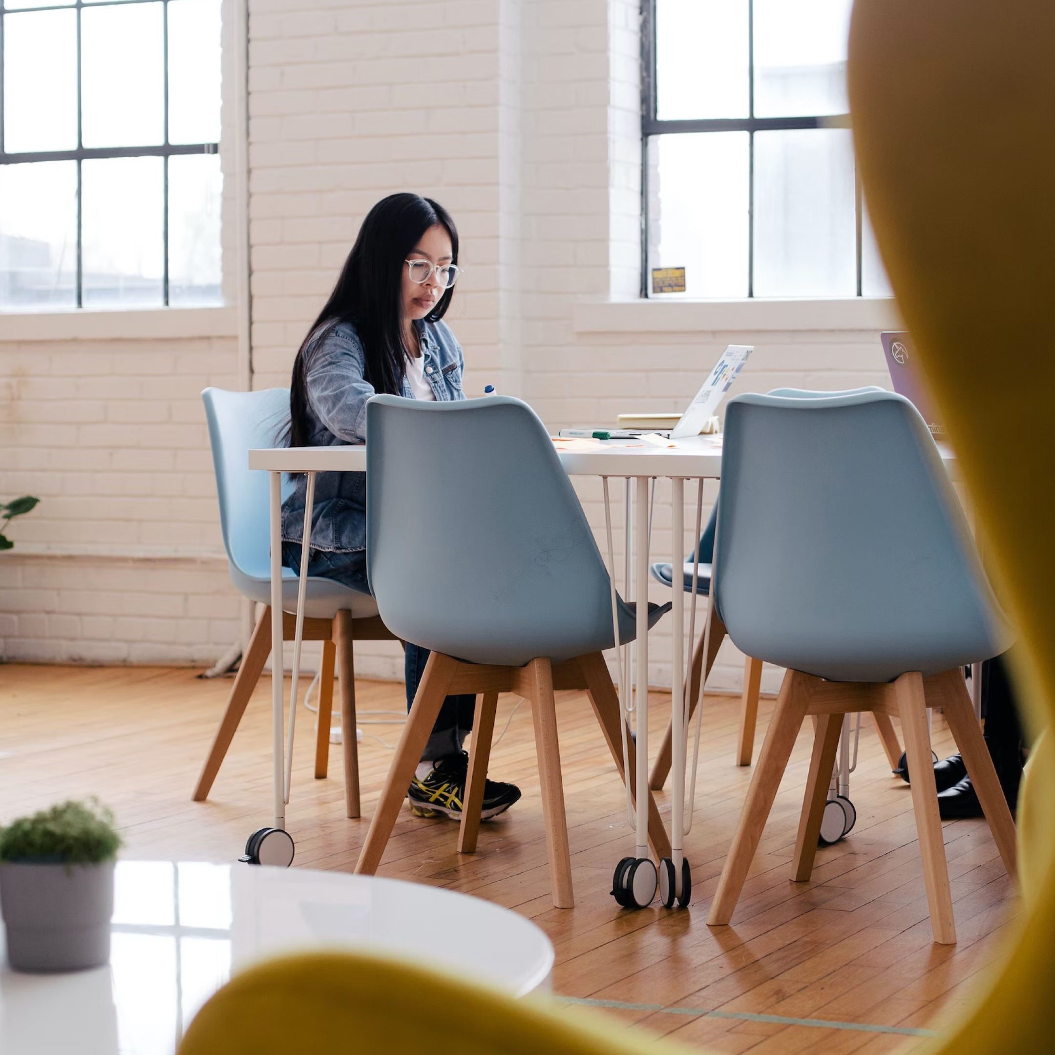 In a bright meeting room, a woman sits by two windows, at a table with her laptop, which is running Carbonite auto backup.